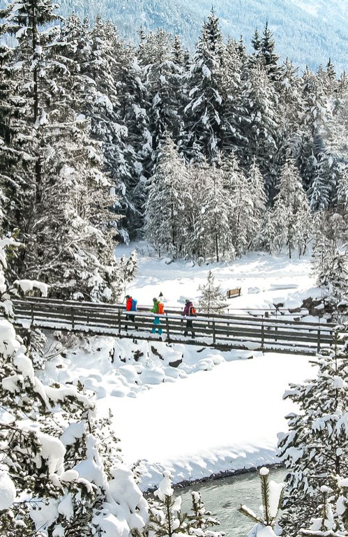 Personen wandern über verschneite Brücke